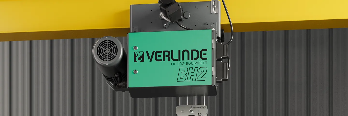 Verlinde BH hoist installed above a conveyor belt with cardboard boxes in a warehouse setting.